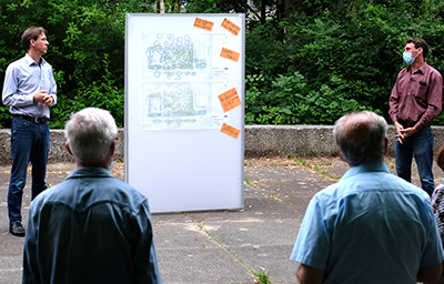 Der Landschaftsplaner erläutert an einer Schautafel im Grünen den Bürgerinnen und Bürgern die geplante Platzgestaltung.