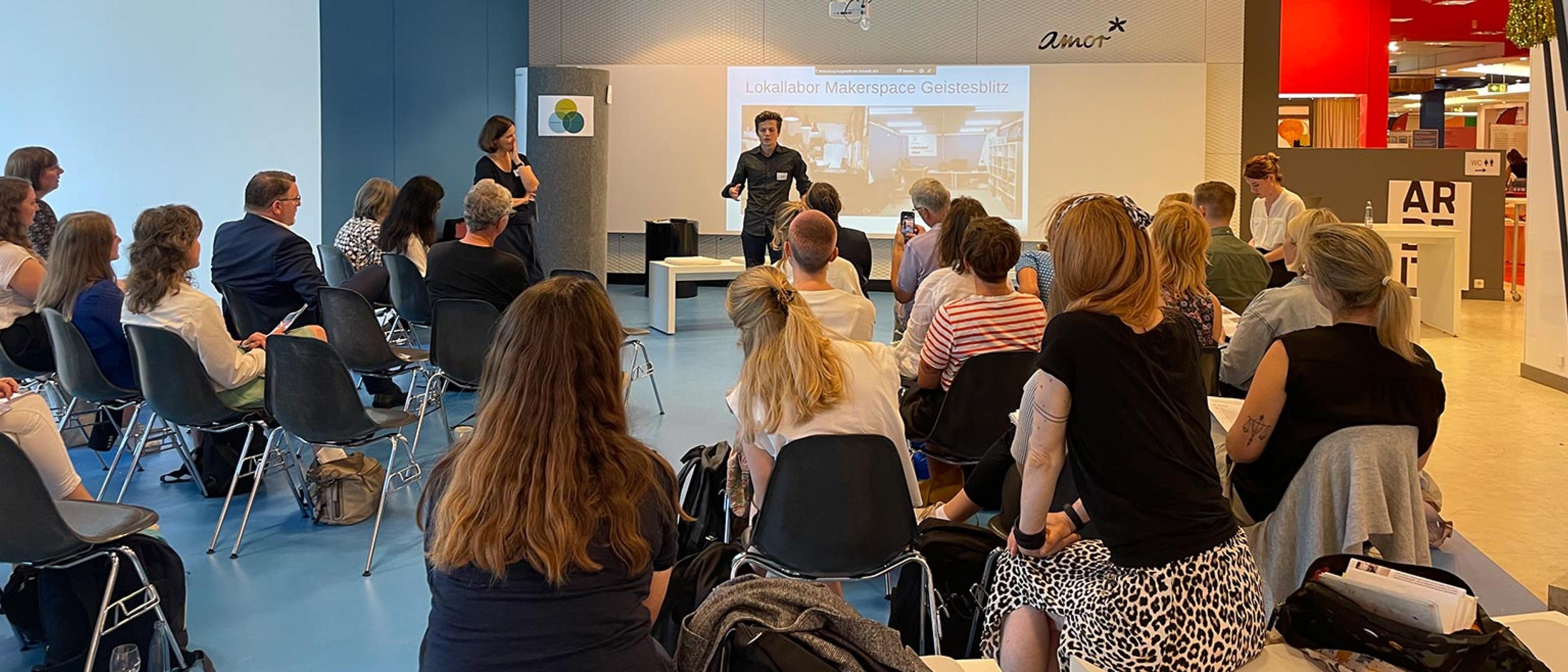 Viele Personen sitzen in einem Workshop