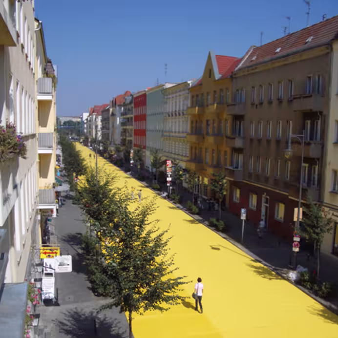 Ein langer gelber Teppich auf der Straße zwischen Häuserschluchten