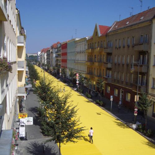 Ein langer gelber Teppich auf der Straße zwischen Häuserschluchten